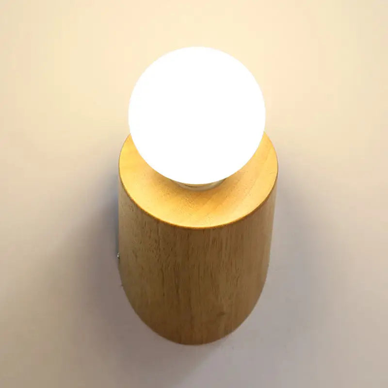 Minimalist wall lamp with warm wood cylindrical base and frosted white light bulb for bedroom or living room use