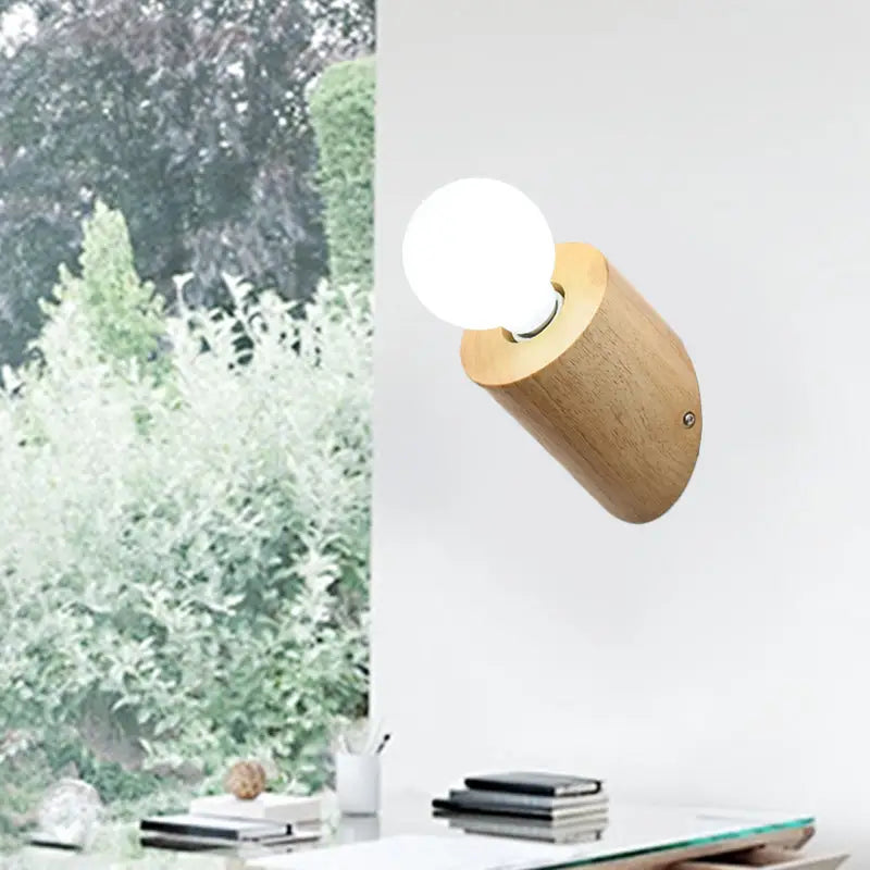 Minimalist wood wall lamp with light-colored cylindrical wood body and frosted glass bulb for bedroom or living room