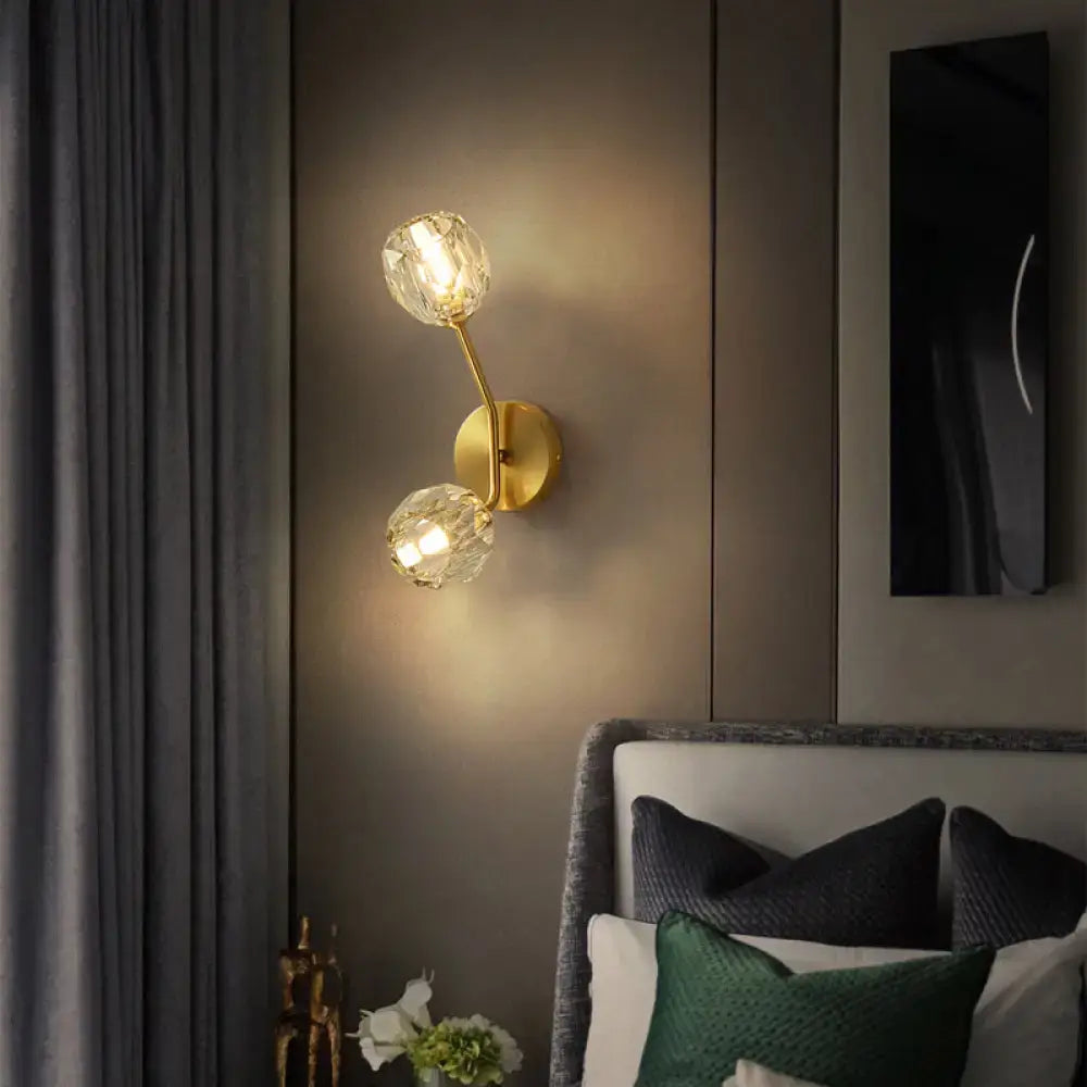 Gold-toned minimalistic brass branch wall light with two faceted crystal globe shades for bedroom wall lamp