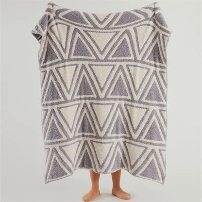 A plush knitted jacquard blanket with mint green and cream geometric pattern for bedroom decor by decorbites