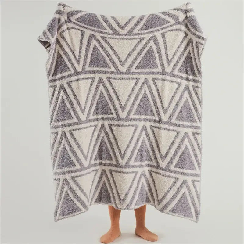 A plush knitted jacquard blanket with mint green and cream geometric pattern for bedroom decor by decorbites
