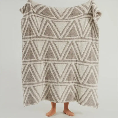 A soft beige and gray textured towel with geometric triangles on a mint green and cream decorbites knitted jacquard blanket