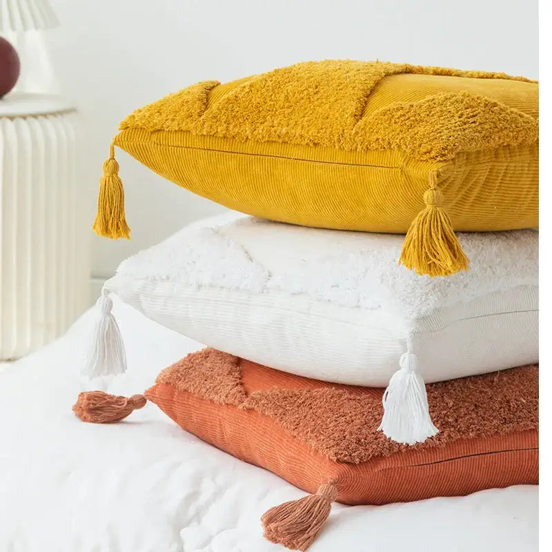 Stack of three textured tassel cushion covers in mustard yellow white and terracotta with diamond tassel details
