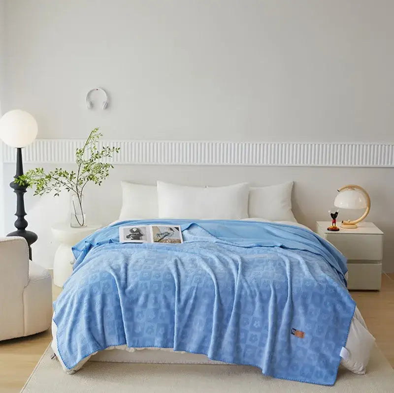 Light blue decorbites jacquard milk velvet throw blanket with subtle geometric pattern draped over bed for travel and decor