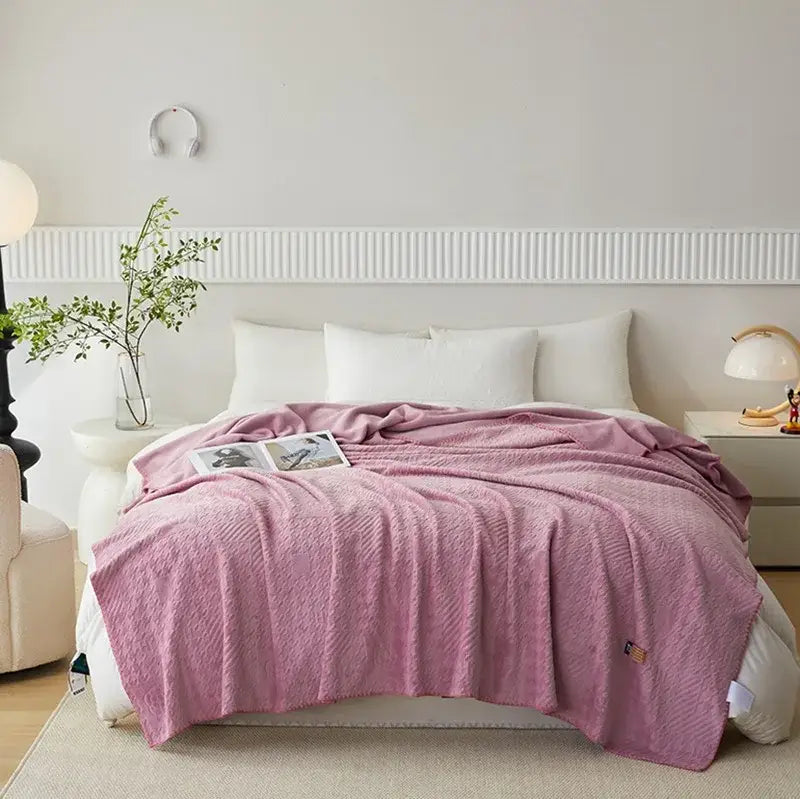 Soft pink textured throw blanket draped over bed featuring jacquard milk velvet fabric by decorbites for bedroom travel use