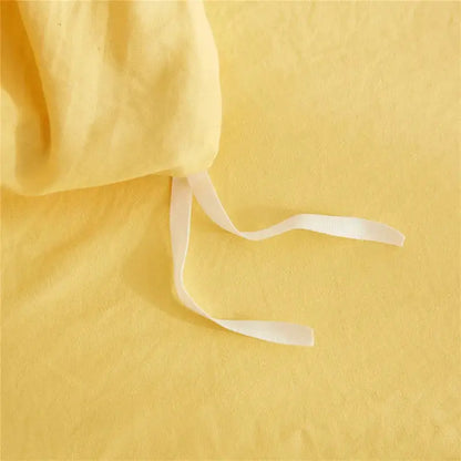 Soft yellow linen fabric with white drawstrings as part of a mint green quilted duvet cover set with pom pom trim