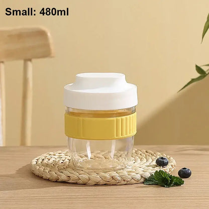 Clear glass travel mug with white lid and yellow ribbed grip band for decorbites breakfast cup kitchen use