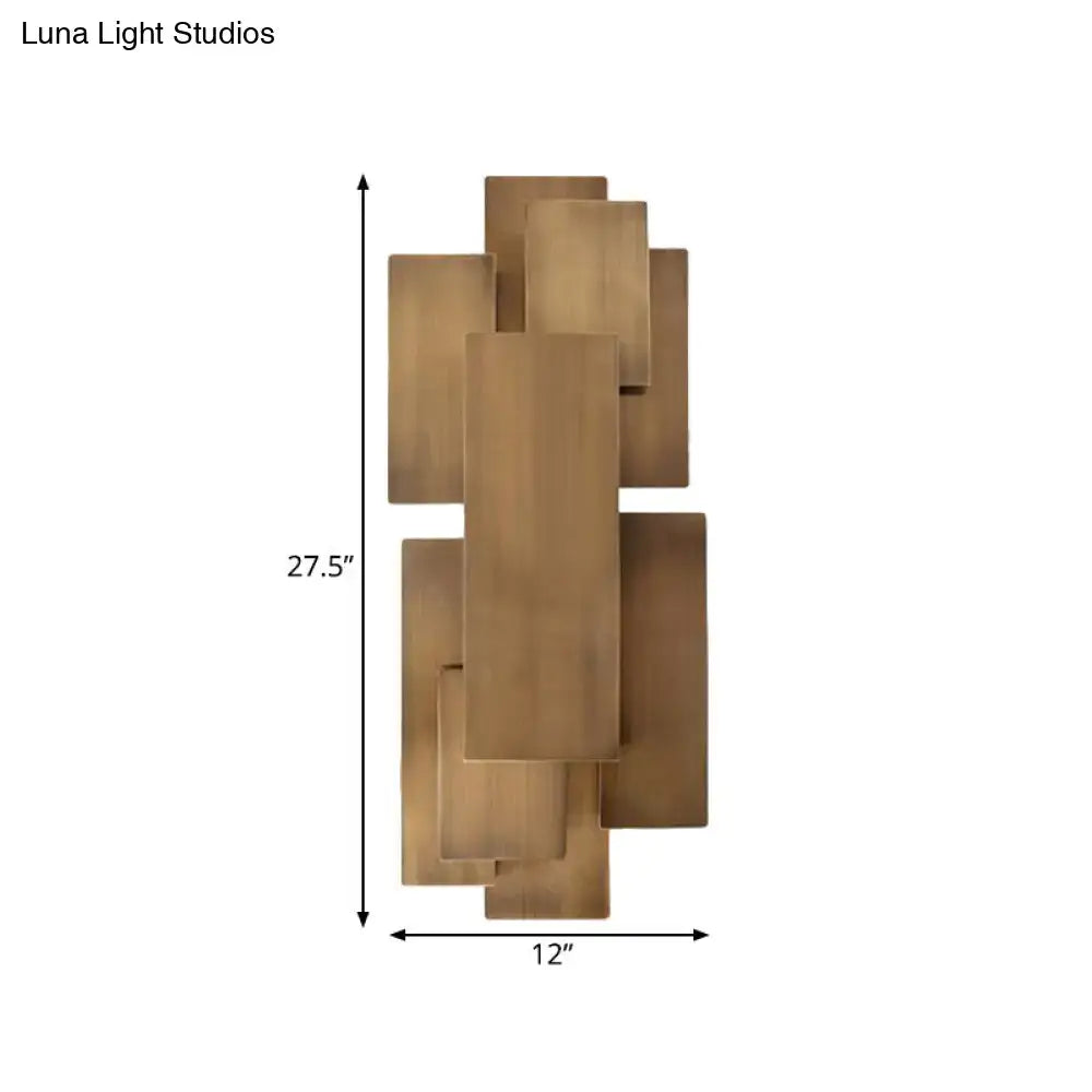Modern brass wall sconce with overlapping rectangular plates mounted on dark wood for direct wired 220v-240v stairway lighting