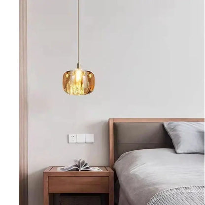 Modern amber and gold crystal led chandelier with a warm amber glass pendant and ribbed design above wooden nightstand