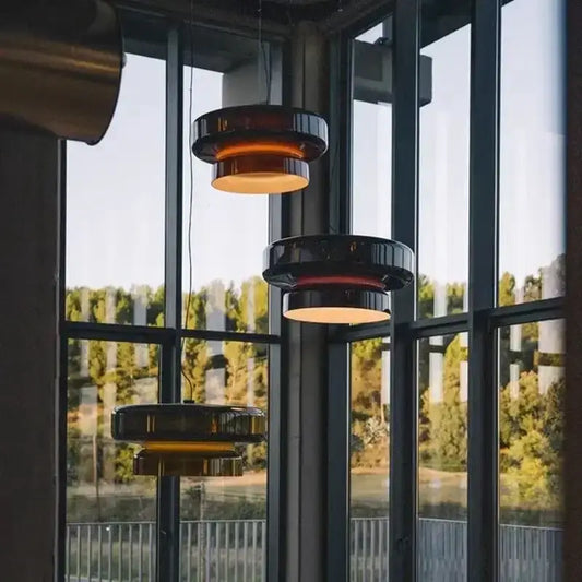 Modern amber and black layered glass pendant light with a sleek circular design for dining room use