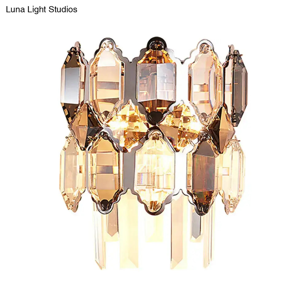 A modern amber and clear crystal wall sconce with faceted cascading glass and brass frame for staircase lighting