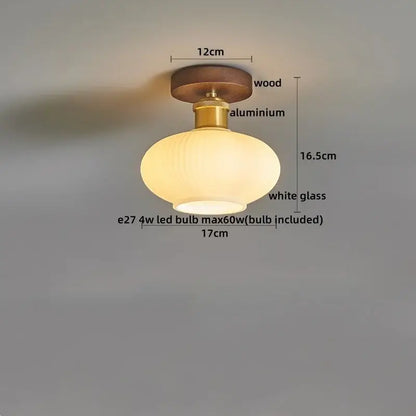 A modern led ceiling lamp with amber glass oval shade, brass aluminum stem, and wooden base for dining room use