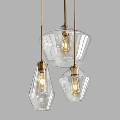 Set of three clear glass pendant lights with brass accents and exposed filament bulbs for living room chandelier