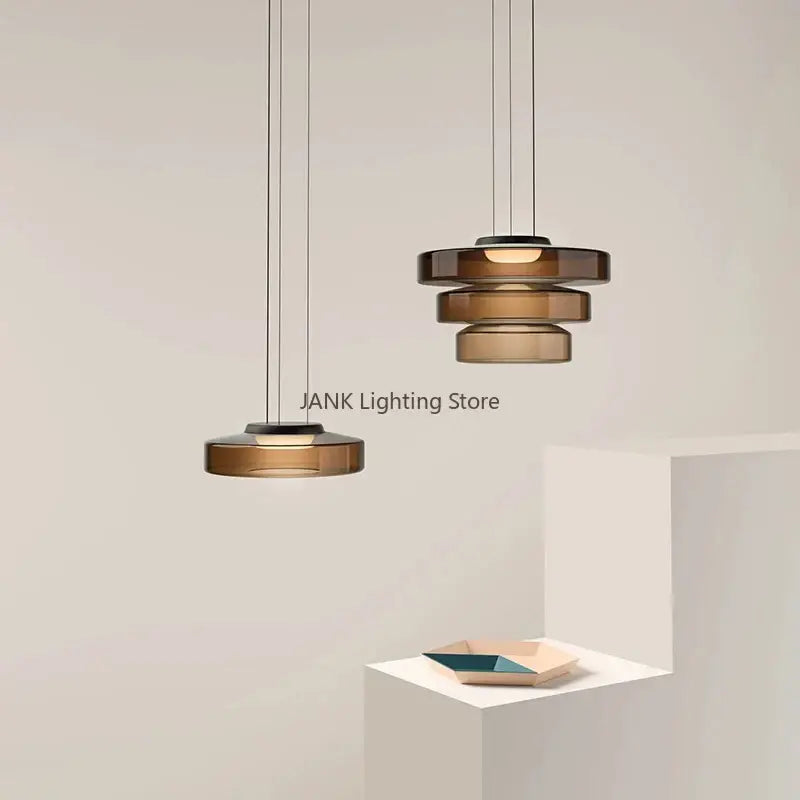 Modern amber glass led pendant lights feature tiered stacked discs and sleek black metal frames for dining room chandelier