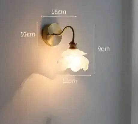 A delicate vintage-style led wall lamp with a brass arm and white ceramic flower shade for bedroom wall sconce