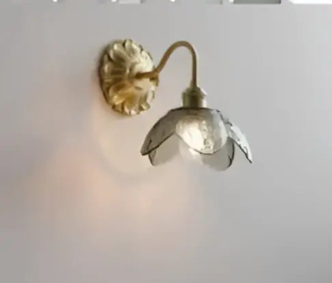 Gold-toned brass modern amber glass led wall lamp with a delicate translucent flower shade for bedroom use