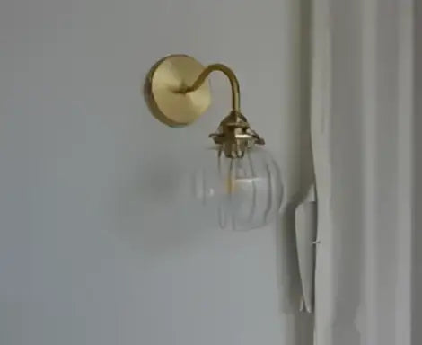 Gold-toned modern amber glass led wall lamp with clear glass globe and brass sconce for bedroom lighting