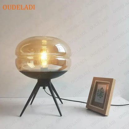 Modern amber glass table lamp with black tripod base featuring exposed filament bulb for bedroom decorbites glass table lamp