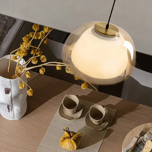Modern amber and gray double glass pendant light featuring a warm glowing glass pendant light with a polished brass base