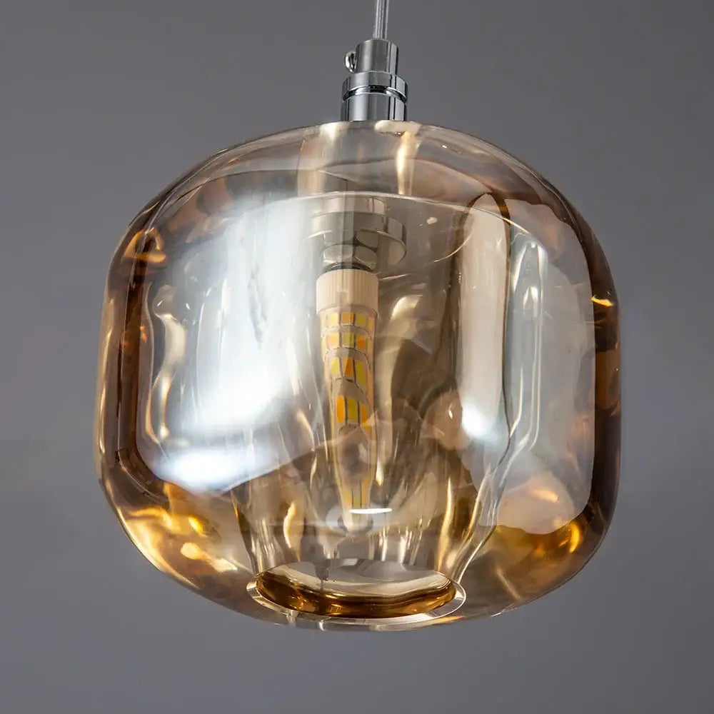 A modern amber-tinted glass pendant light with led bulb as part of a crystal staircase chandelier for dining room