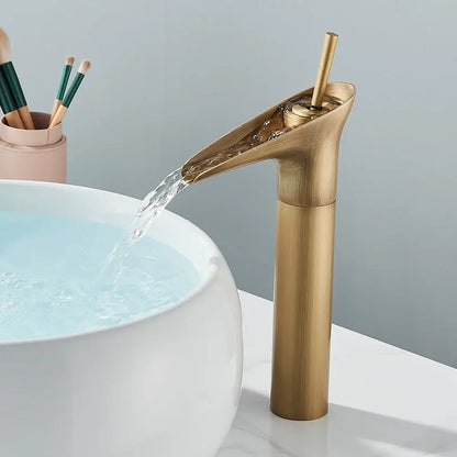 Modern antique brass finish waterfall faucet with matte black accents and sleek cylindrical spout for bathroom sink tap