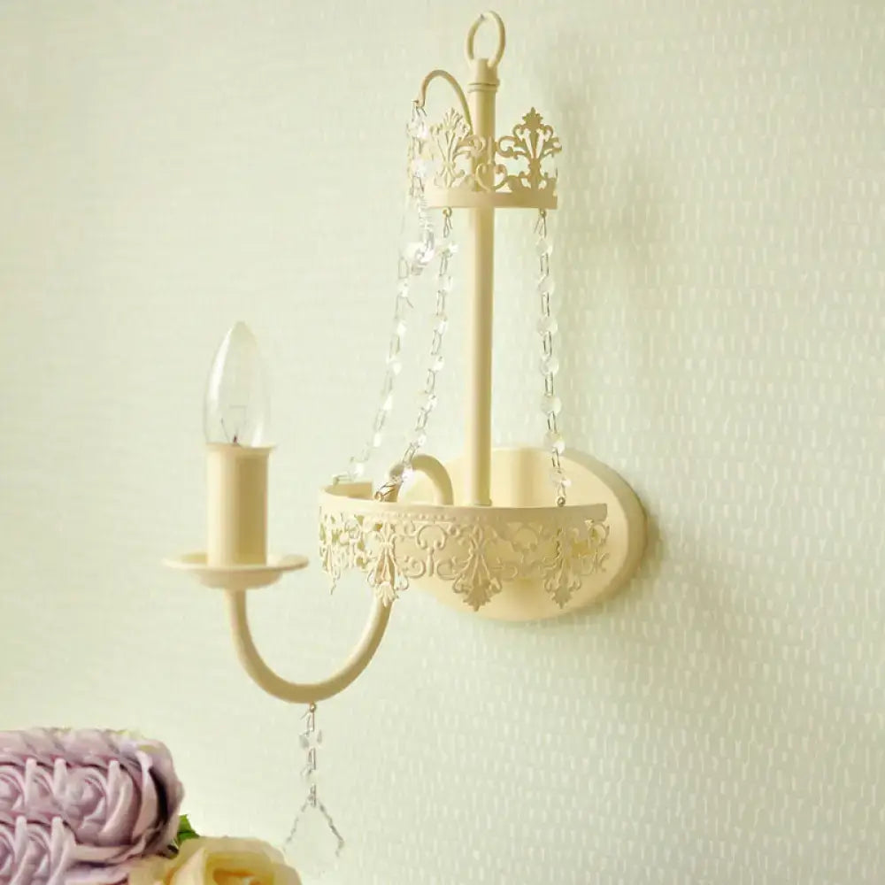 Beige ornate metal wall sconce with crystal chains and candle-style bulb 15 inch fixture for modern bedrooms