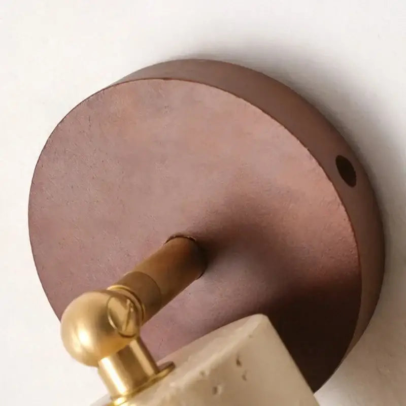Modern beige stone and bronze wall light fixture with copper-toned circular sconce and textured concrete shade