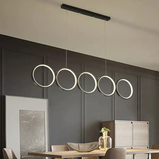 Modern black metal pendant light features five illuminated circular LED rings in a row for hanging island light use