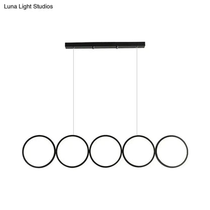 Black metal DecorBites pendant light with five circular rings hanging from a rectangular bar for island lighting