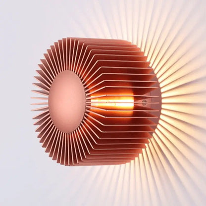 Modern black aluminum wall sconce with copper-colored radial design and warm filament bulb for elegant living room lighting