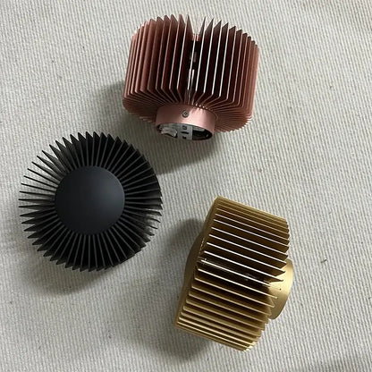 Three heat sinks in rose gold black and brass finishes complement an elegant aluminum wall sconce for living room use