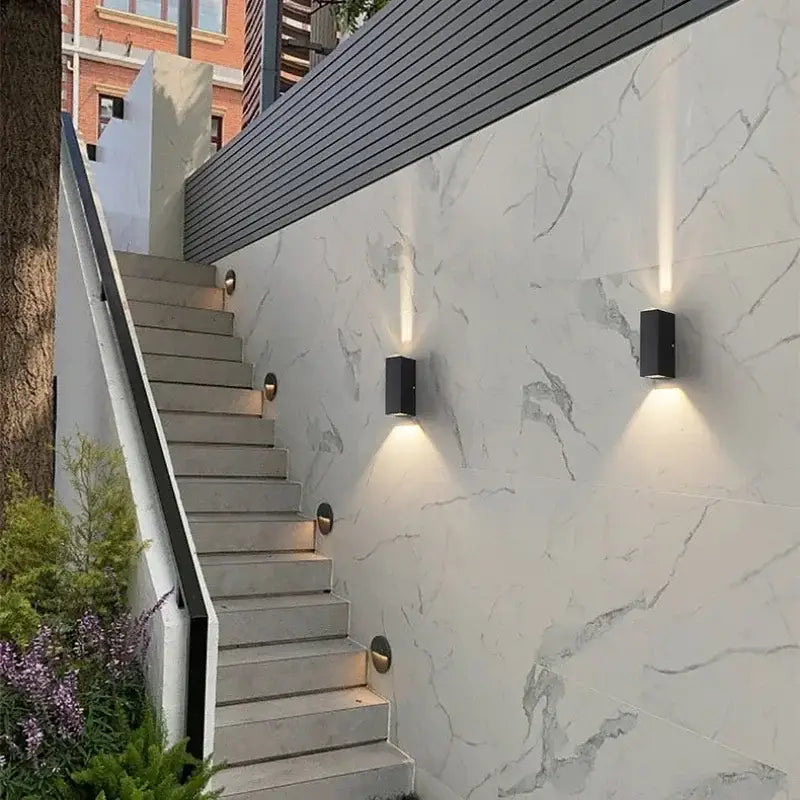 Modern black aluminum waterproof porch spot wall lamp with sleek minimalist design illuminating white marble wall