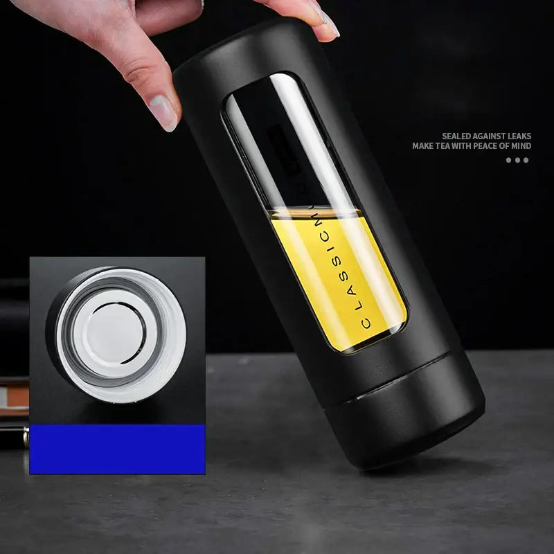 Modern black and amber insulated glass water bottle with transparent window showing yellow liquid and silver lid for travel