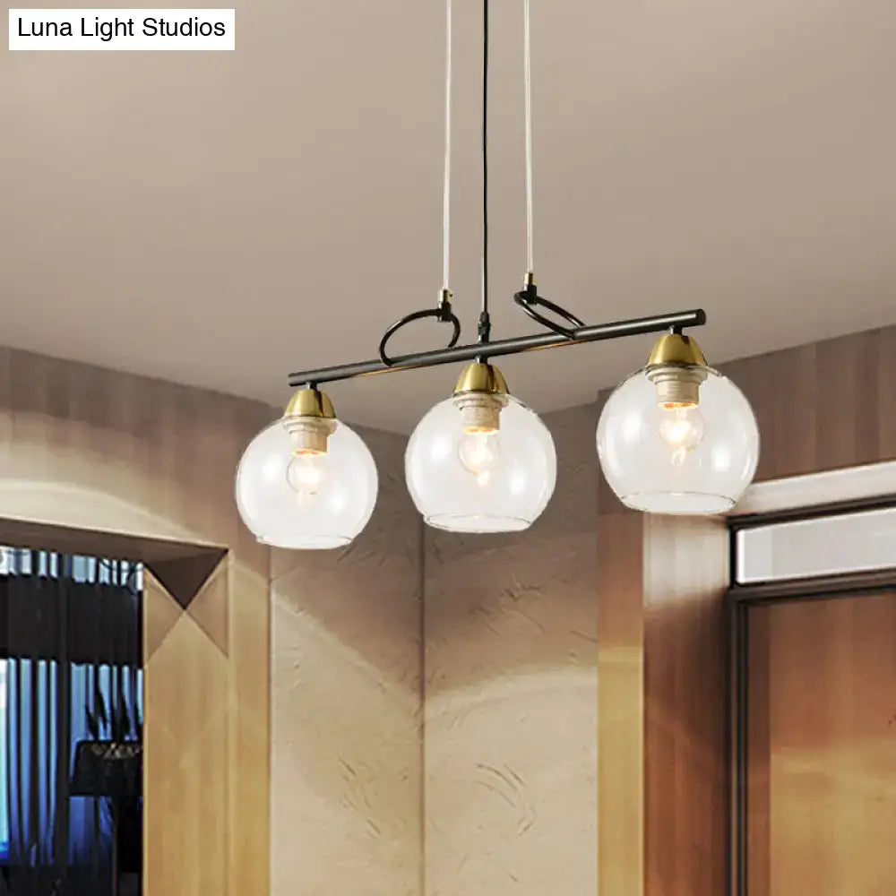 Modern three-light pendant fixture with smoke gray glass globes and brass accents for hall island lighting