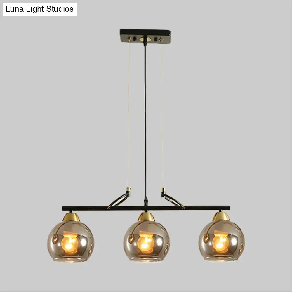 Modern black metal chandelier with three smoke gray glass globe shades and brass accents for hall island lighting