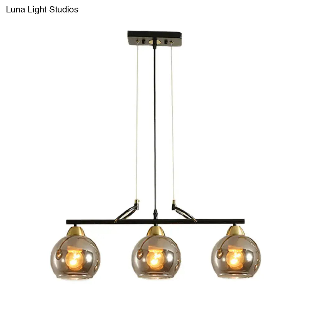 Modern black metal chandelier with three smoke gray glass globes and brass accents for hall island lighting
