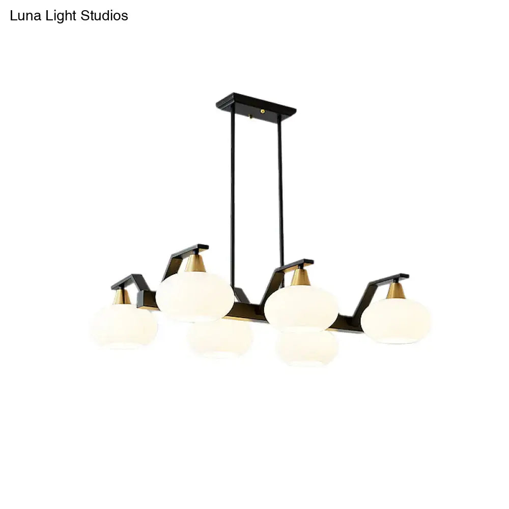 Modern black linear hanging lamp with brass accents and five frosted opal glass globes ideal for dining room island lighting