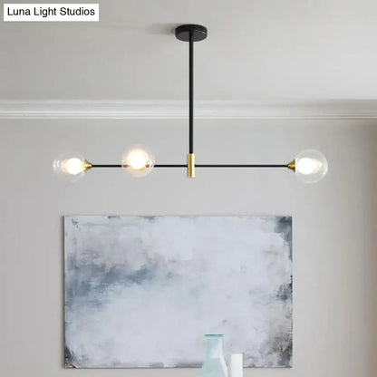 Modern black and brass metal island pendant with three clear glass globe bulbs and adjustable chain cord length for dining room chandelier