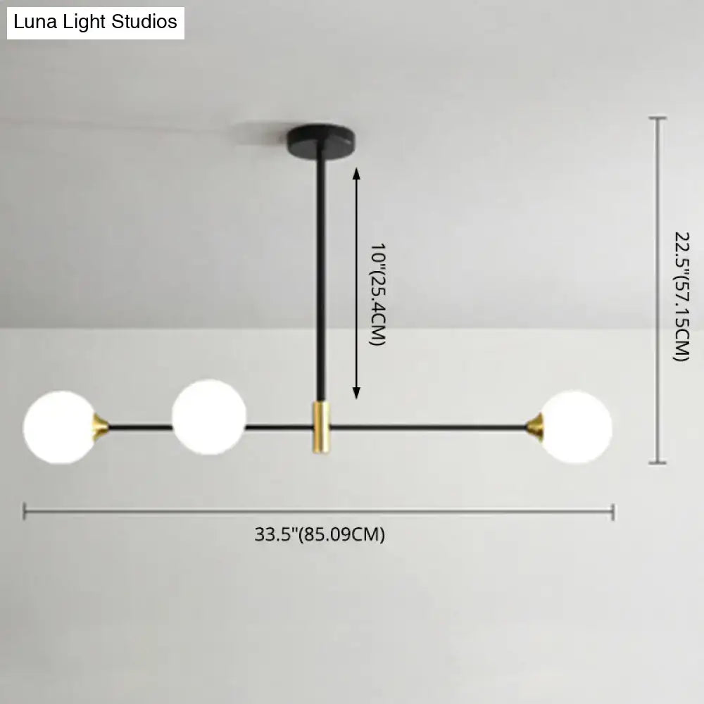 Modern black metal island pendant with brass accents and three frosted glass globes for dining room lighting adjustable chain cord length