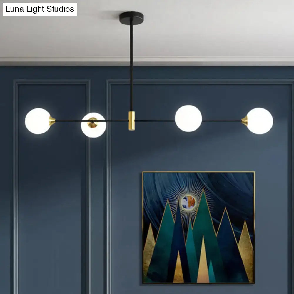 Modern black metal island pendant with brass accents and three white glass bulbs featuring adjustable chain cord length
