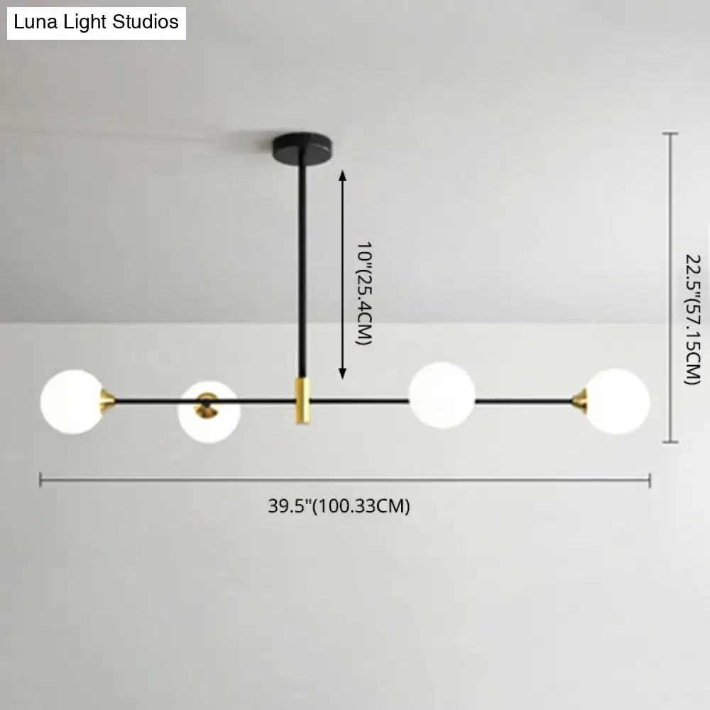 Modern black metal island pendant with brass accents and four frosted glass globe bulbs featuring adjustable chain cord length