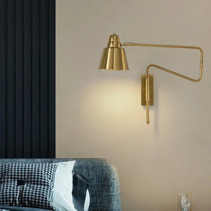 Brass-finished modern wall sconce with conical shade and black retractable arm for bedroom reading light