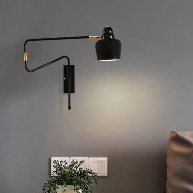 Modern black and brass wall-mounted reading lamp with sleek retractable arm for bedroom lighting