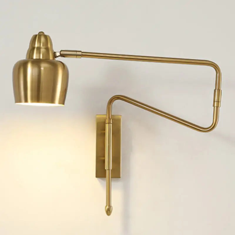 Brass-finished adjustable wall sconce with sleek articulated arm and cylindrical lamp head featuring retractable arm design