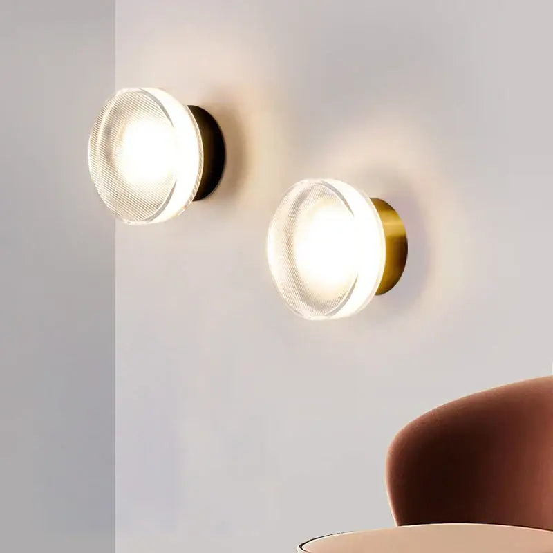 Modern black and clear acrylic wall sconce light with frosted glass diffusers and brass-finished metal bases for bedroom use