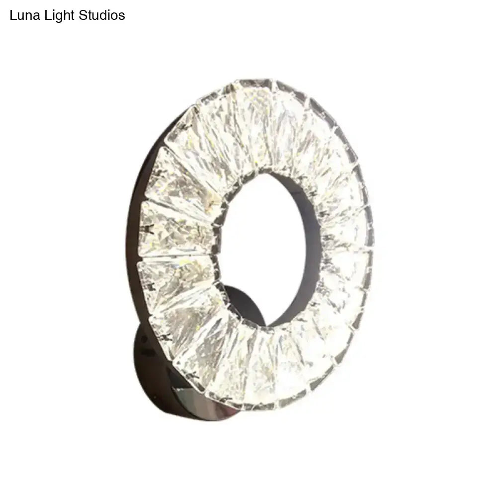 Modern black and crystal chrome wall sconce with faceted crystals emitting warm bright color temperature light