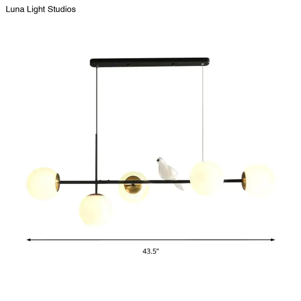 Modern black metal pendant light with five frosted glass shades and white ceramic dove on central bar for island pendant use