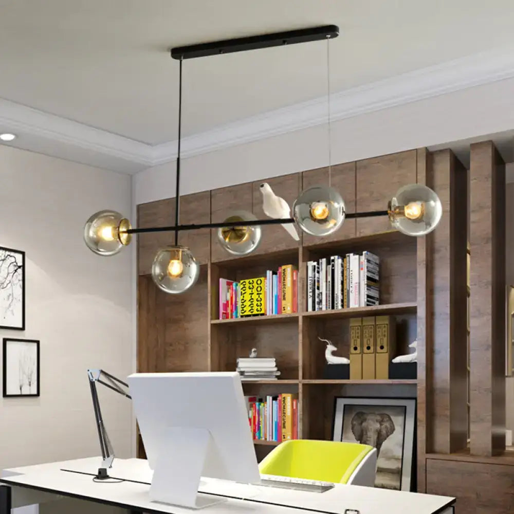 Modern black metal pendant light with five clear glass globe bulbs and white ceramic bird on central bar for island pendant use