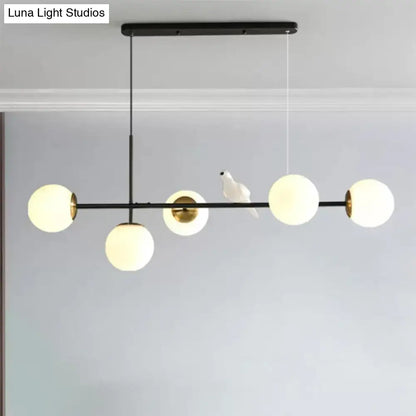 Modern DecorBites™ brass sphere pendant light with five frosted glass shades and adjustable cord for island pendant use