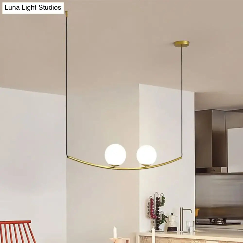 Modern brass pendant light with two white glass bulbs and curved arm in black gold bubble island light design